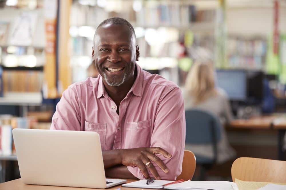 Middle Aged man sitting by his laptop and smiling